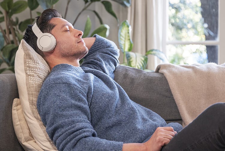Man in casual clothing relaxing indoors on couch with headphones